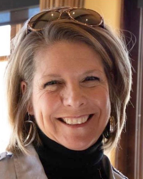 Danielle L. Atkinson wearing a black turtleneck and a light-colored jacket, smiling at the camera